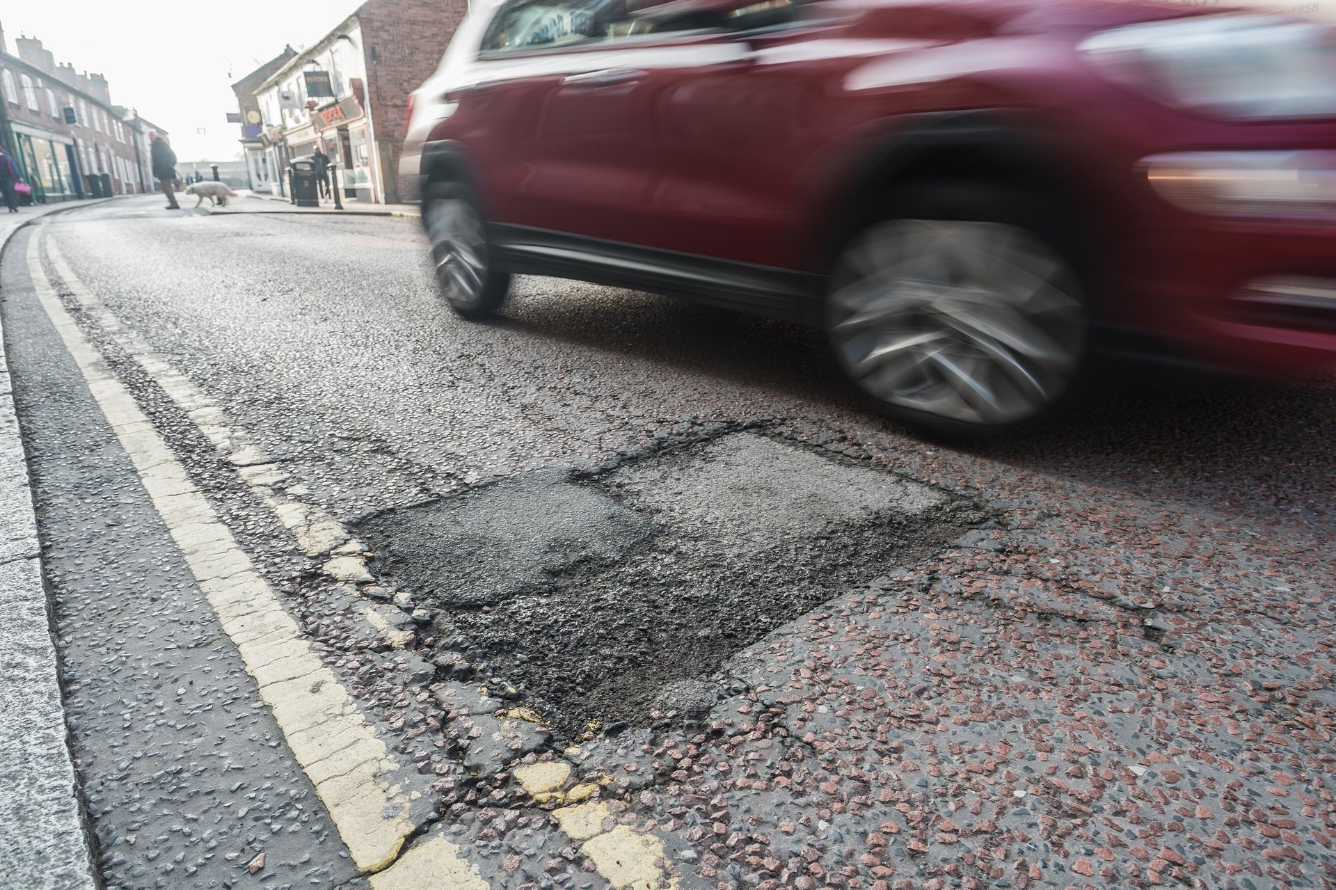 Car driving past a pothole