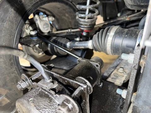 Close-up of vehicle suspension system showing shock absorber, springs, and brake components