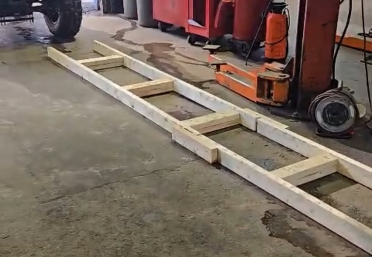 Wooden ladder or beam lying on a wet asphalt surface with parked vehicles in the background
