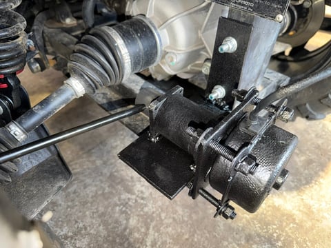 Close-up of automotive engine components showing drive belts, pulleys, and metal mechanical parts on concrete surface